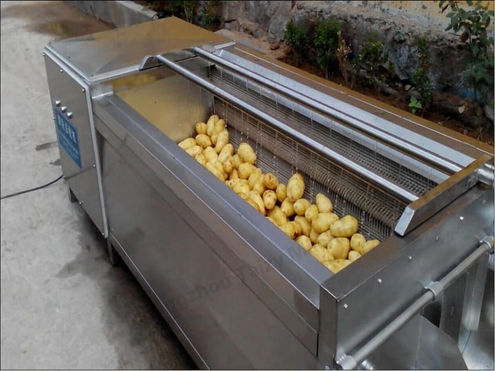 The brush machine is cleaning potatoes.